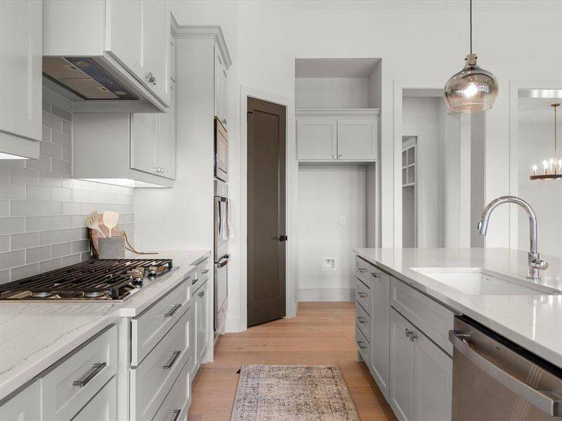 Kitchen with light stone counters, stainless steel appliances, light wood finished floors, pendant lighting, and white cabinets Kitchen with light stone counters, stainless steel appliances, light wood finished floors, pendant lighting, and white cabinets