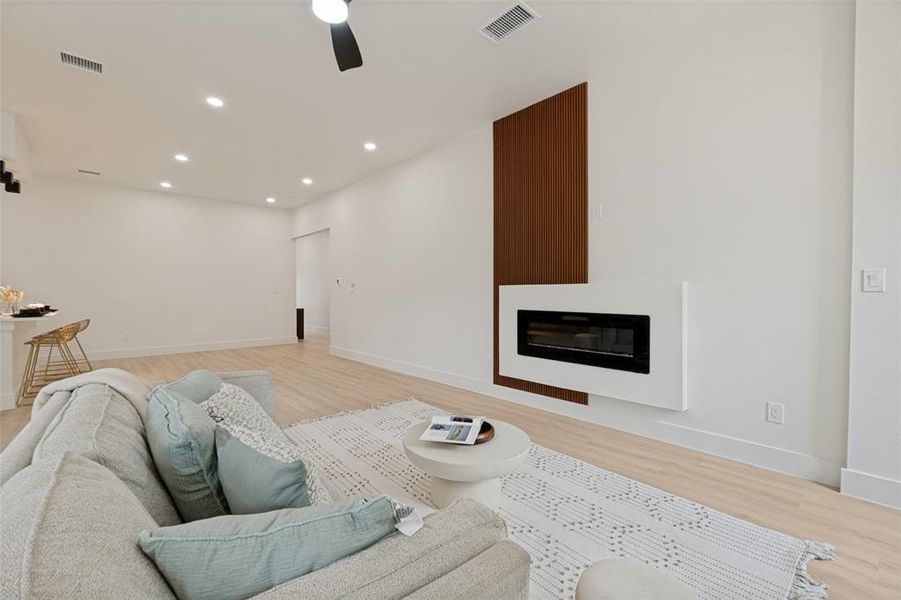 Contemporary living space featuring a linear electric fireplace with a white surround and a wood-finish accent panel
