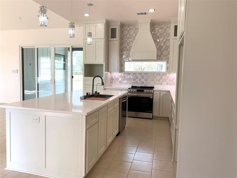 Kitchen featuring decorative backsplash, stainless steel appliances, light tile patterned floors, a kitchen island with sink, and plenty of natural light Kitchen featuring decorative backsplash, stainless steel appliances, light tile patterned floors, a kitchen island with sink, and plenty of natural light