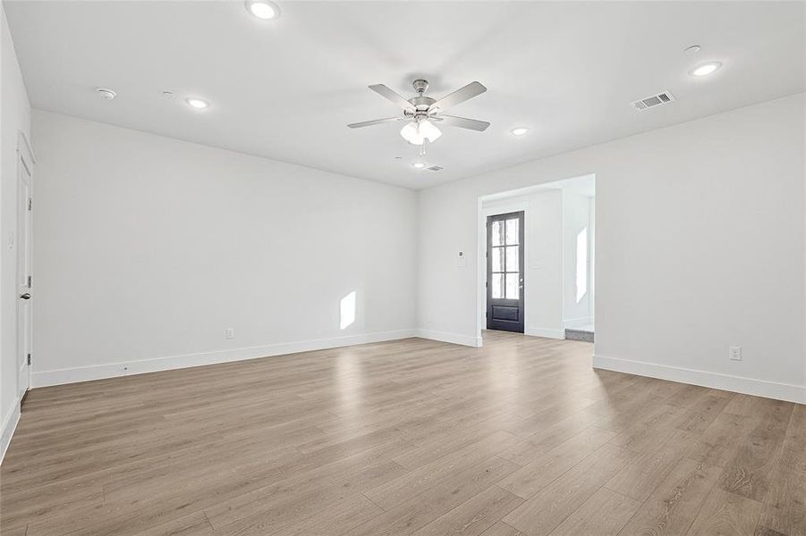 Spacious room featuring light-toned flooring, white walls, recessed lighting, and a ceiling fan