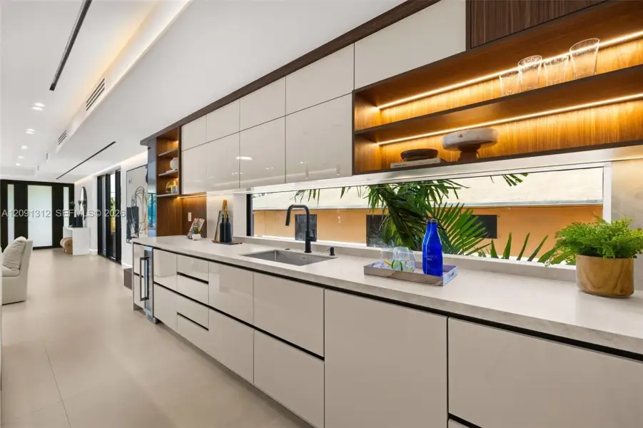 Sleek cabinetry with high-gloss finish, minimalist stone countertops, linear undermount stainless steel sink, matte black faucet, and recessed integrated shelving with accent lighting Sleek cabinetry with high-gloss finish, minimalist stone countertops, linear undermount stainless steel sink, matte black faucet, and recessed integrated shelving with accent lighting