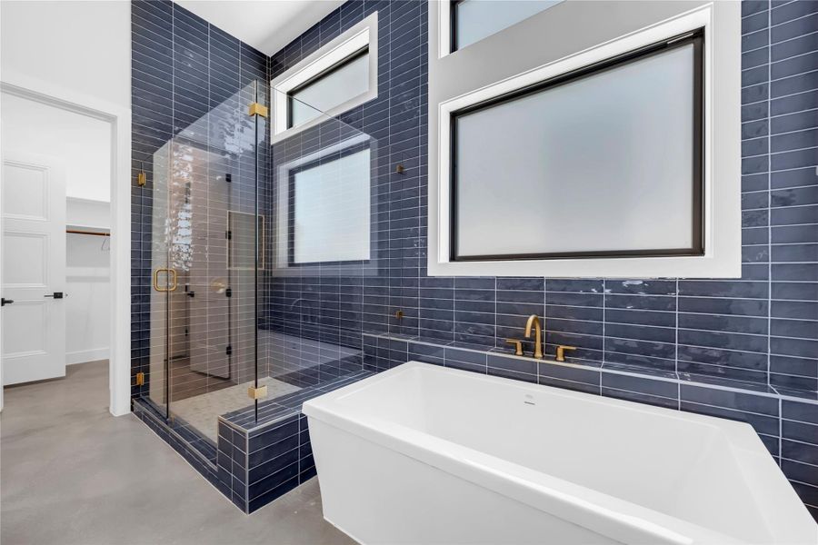 Bold tile surrounds a freestanding soaking tub and a spacious glass-enclosed shower.