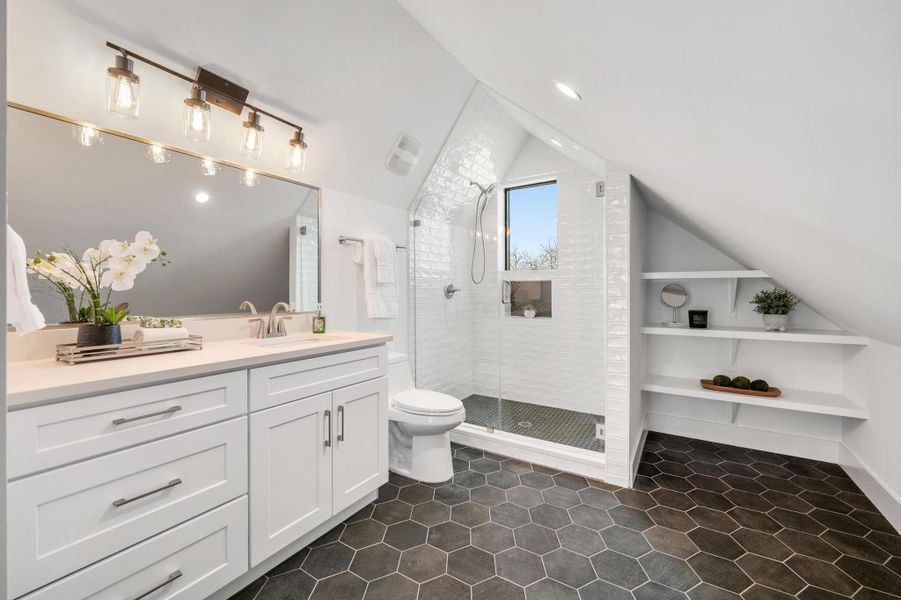 Full bathroom featuring tile patterned flooring, a shower stall, toilet, lofted ceiling, and vanity