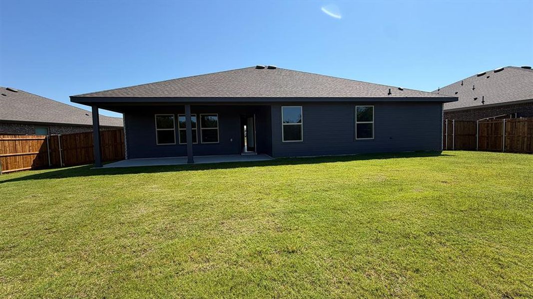 Expansive green lawn with a covered patio, multiple windows, and a privacy fence Expansive green lawn with a covered patio, multiple windows, and a privacy fence
