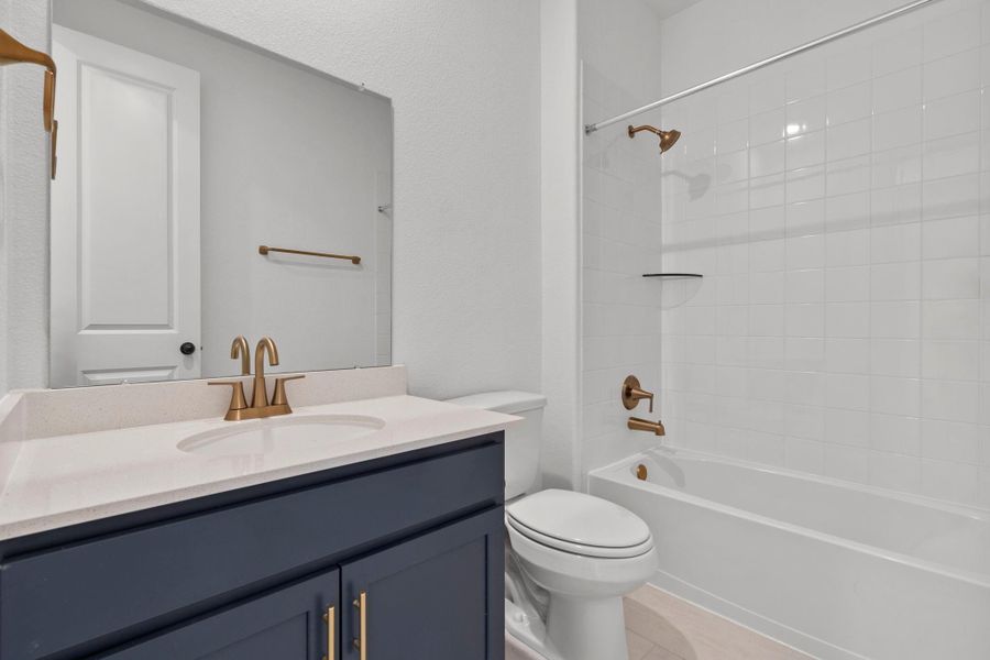The secondary bath features tile flooring, custom stained cabinetry and light countertops and a shower/tub combo. Perfect for accommodating any visiting family and friends.