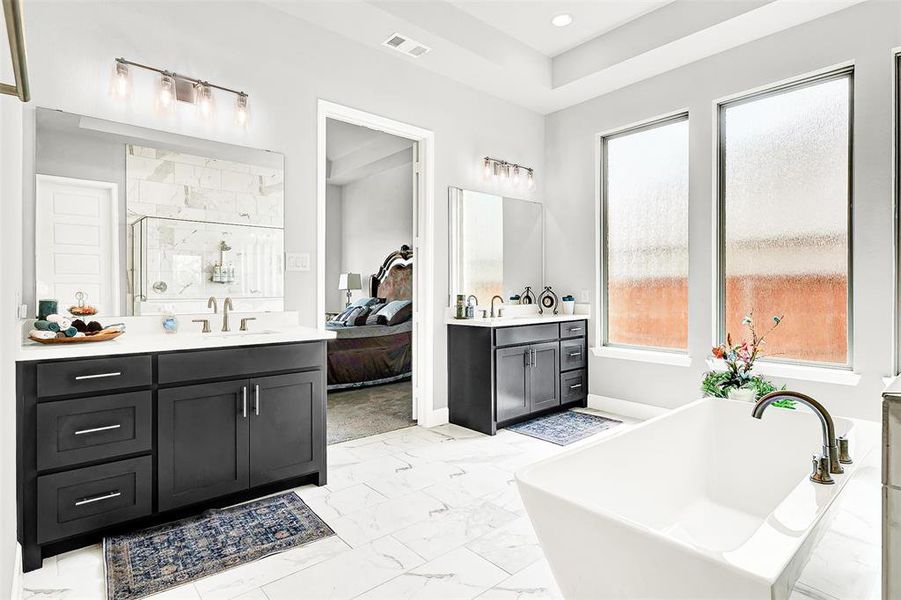 Bathroom with a shower stall, two vanities, light marble finish flooring, a freestanding tub, and connected bathroom