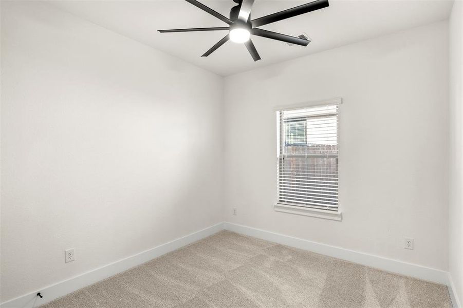Carpeted spare room with baseboards and a ceiling fan