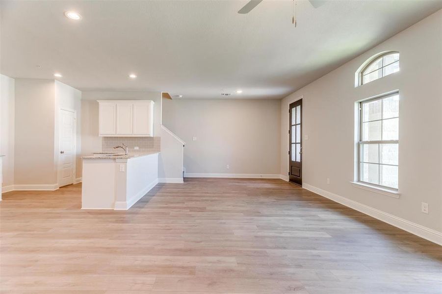 Kitchen featuring white cabinetry, light stone countertops, decorative backsplash, kitchen peninsula, and light wood-type flooring