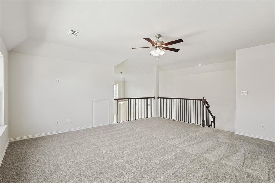 Empty room featuring carpet, ceiling fan, and vaulted ceiling