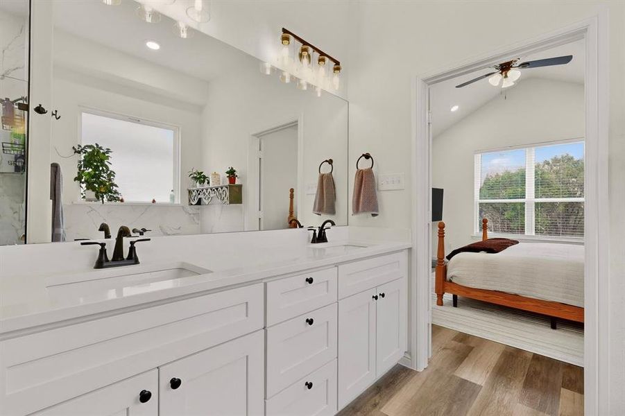 Bathroom vanity featuring dual sinks, white cabinetry, and a full-width mirror