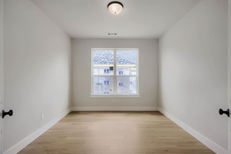 Room featuring wood-finish flooring, a double-paned window, neutral wall paint, white baseboards, and a flush-mount ceiling light fixture