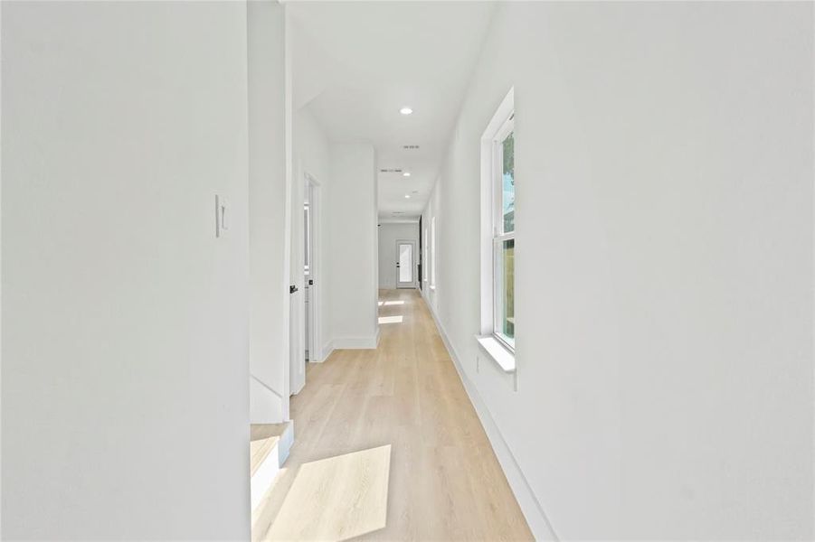 Hallway with light wood-style flooring and recessed lighting