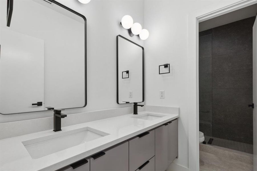 Bathroom with toilet and dual bowl vanity