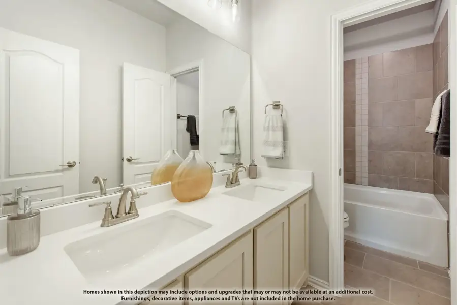 Bathroom with double sink vanity, white countertop, and tiled bathtub surround
