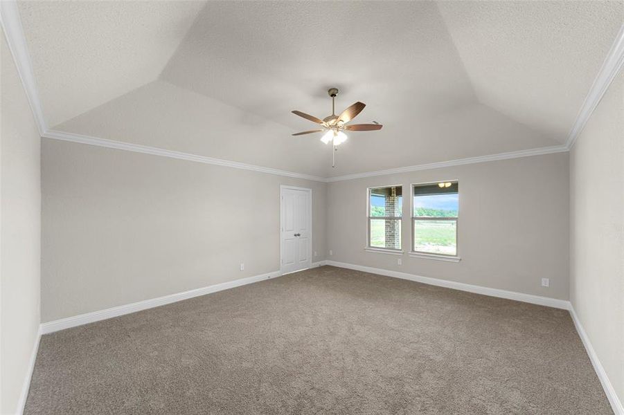 Vaulted ceiling featuring a ceiling fan, crown molding, double windows, a paneled door, and carpet flooring