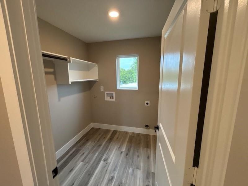 Washroom featuring washer hookup, light wood-style flooring, and electric dryer hookup Washroom featuring washer hookup, light wood-style flooring, and electric dryer hookup