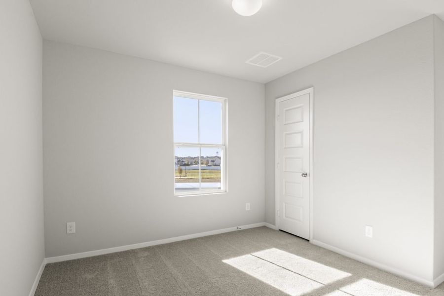 Image of a bedroom with light grey walls, brown carpeting and a window