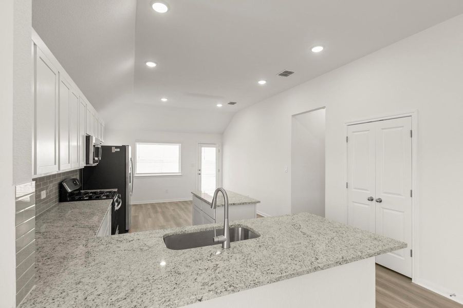 Kitchen featuring a peninsula, white cabinetry, appliances with stainless steel finishes, light wood-style flooring, and lofted ceiling