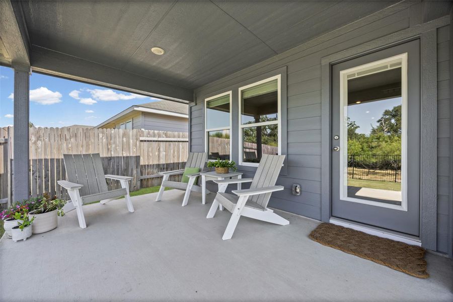 A covered concrete patio provides a comfortable outdoor retreat overlooking the backyard.