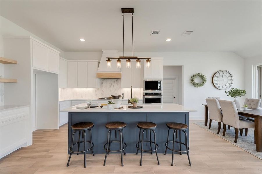 Kitchen featuring oven, built in microwave, premium range hood, white cabinets, and tasteful backsplash Kitchen featuring oven, built in microwave, premium range hood, white cabinets, and tasteful backsplash