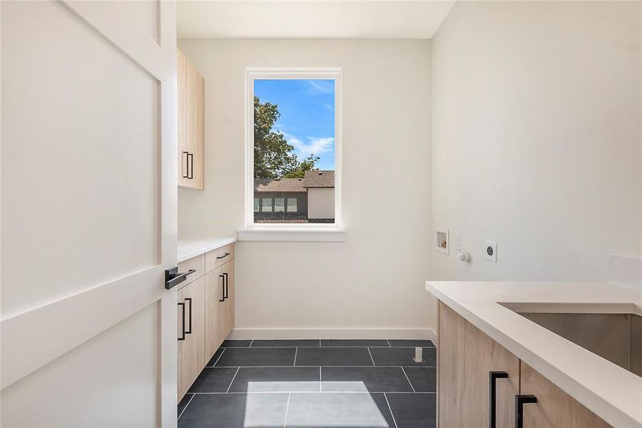 Clothes washing area with cabinets, hookup for an electric dryer, dark tile patterned flooring, and washer hookup