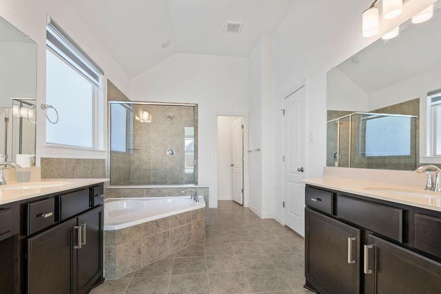 Bathroom with vaulted ceiling, two vanities, a bath, a shower stall, and light tile patterned floors Bathroom with vaulted ceiling, two vanities, a bath, a shower stall, and light tile patterned floors