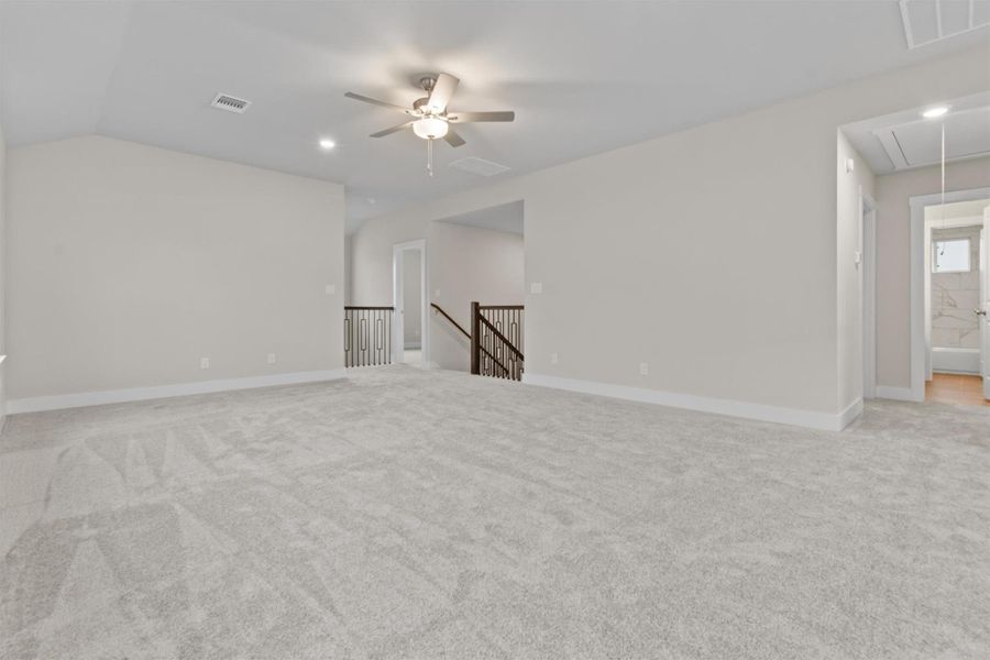 Empty room with ceiling fan, lofted ceiling, and light colored carpet