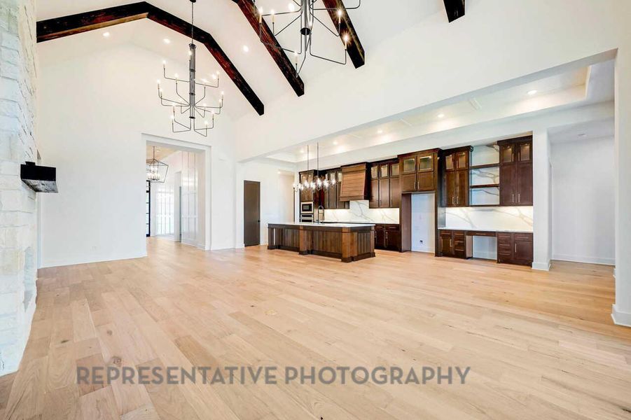 Kitchen with open floor plan, light countertops, light wood-type flooring, hanging light fixtures, and decorative backsplash Kitchen with open floor plan, light countertops, light wood-type flooring, hanging light fixtures, and decorative backsplash