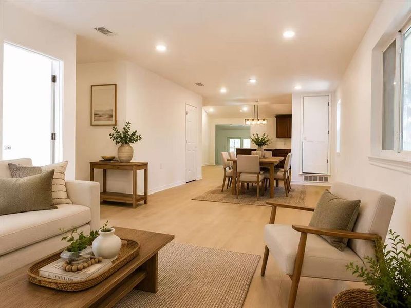Open-concept living area with light wood-finish flooring, recessed lighting, and white walls Open-concept living area with light wood-finish flooring, recessed lighting, and white walls