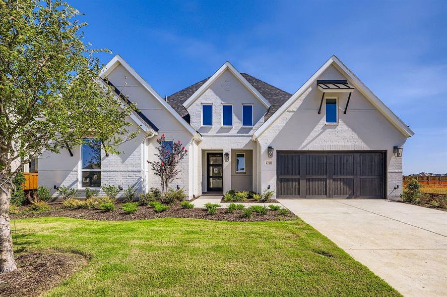 View of front of home with brick siding, concrete driveway, a front yard, and a shingled roof