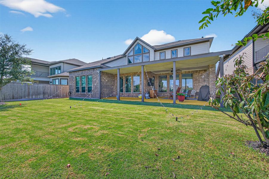 This photo showcases a spacious backyard with a well-maintained lawn, a large covered patio, and a modern two-story home featuring brick and siding. The patio offers ample space for outdoor seating, perfect for entertaining or relaxing. This photo showcases a spacious backyard with a well-maintained lawn, a large covered patio, and a modern two-story home featuring brick and siding. The patio offers ample space for outdoor seating, perfect for entertaining or relaxing.