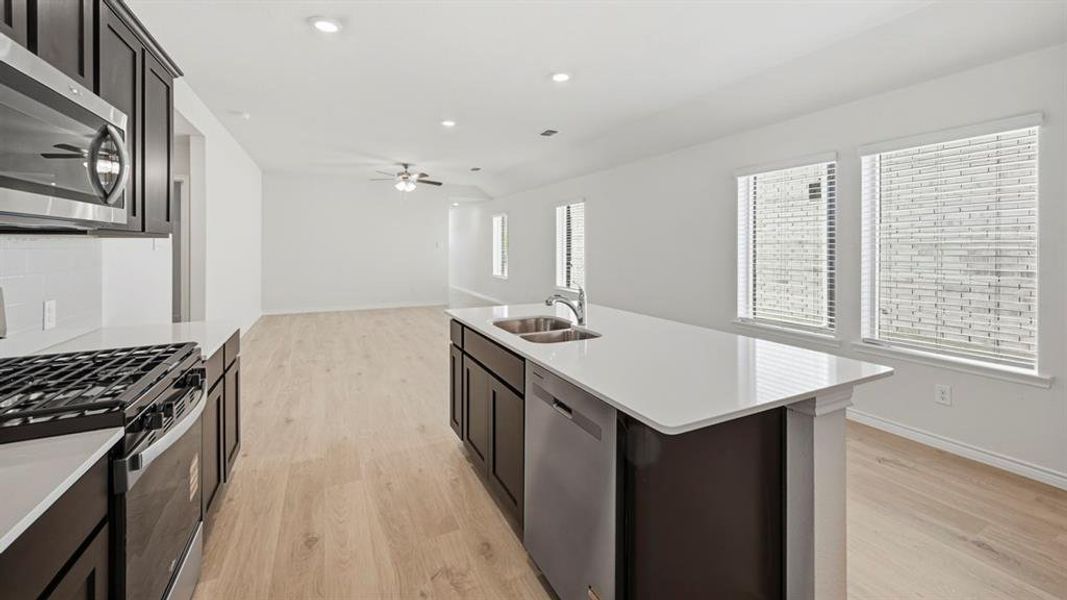 Kitchen with appliances with stainless steel finishes, light wood-style floors, recessed lighting, open floor plan, and light stone counters