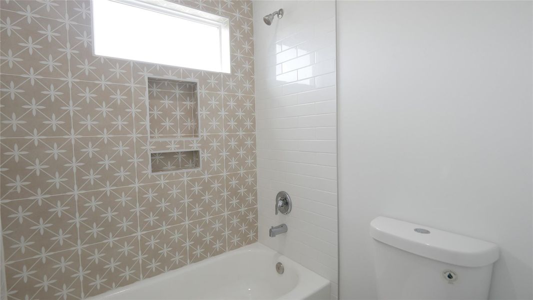 This bathroom features a modern design with a bathtub, stylish patterned tiles, built-in shelving, and a window for natural light. This bathroom features a modern design with a bathtub, stylish patterned tiles, built-in shelving, and a window for natural light.