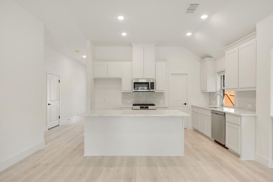 White kitchen with center island, stainless steel appliances, white cabinets, and light wood floors White kitchen with center island, stainless steel appliances, white cabinets, and light wood floors