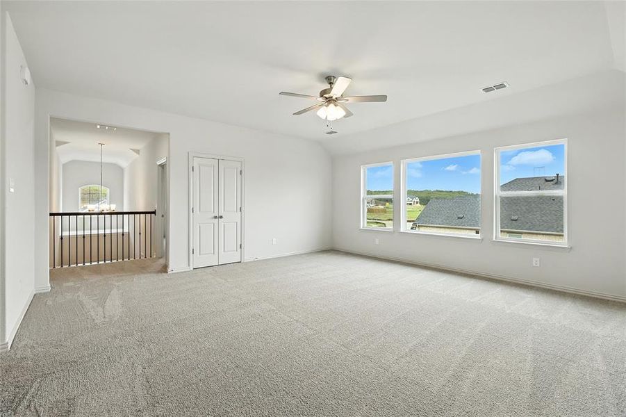 Spare room featuring ceiling fan, suspended lighting, lofted ceiling, and light carpet
