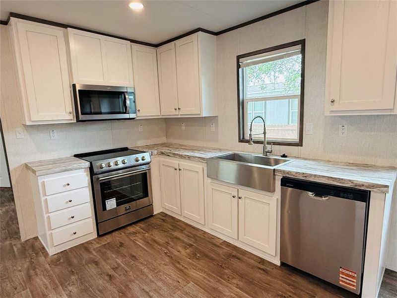 Kitchen featuring white cabinetry, stainless steel appliances, dark wood-style floors, and a sink