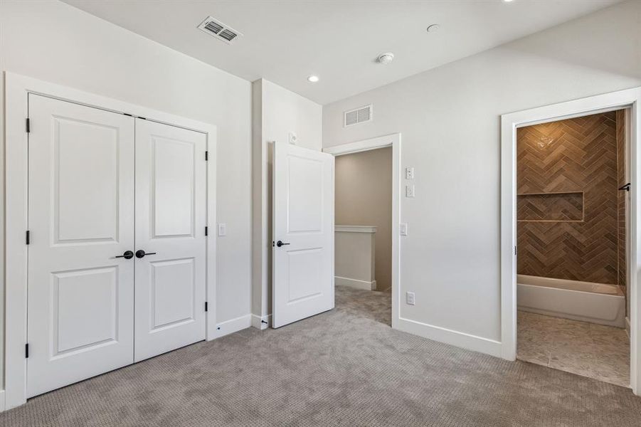 Guest bedroom with ensuite bathroom, light colored carpet, a closet, and recessed lighting