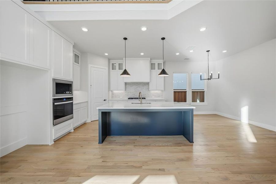 Kitchen with white cabinets, decorative light fixtures, and recessed lighting