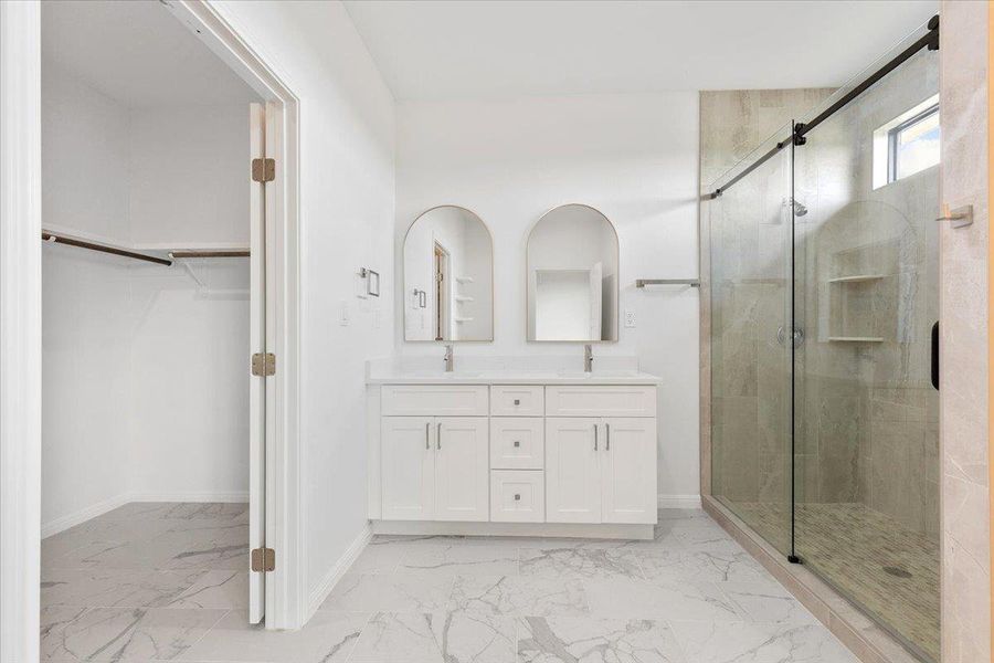 A well-appointed primary bathroom showcases a double vanity and a glass-enclosed shower. A well-appointed primary bathroom showcases a double vanity and a glass-enclosed shower.
