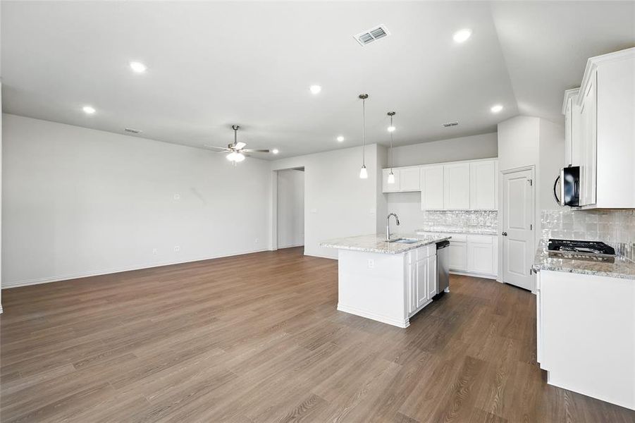 Kitchen with tasteful backsplash, an island with sink, light stone countertops, dark wood finished floors, and open floor plan Kitchen with tasteful backsplash, an island with sink, light stone countertops, dark wood finished floors, and open floor plan