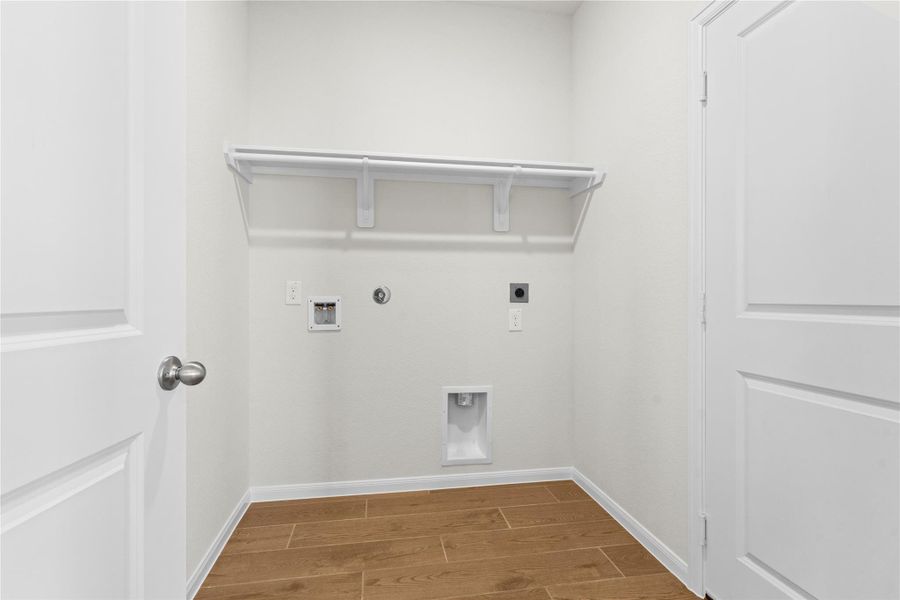 Convenient utility room located on the first floor featuring washer and dryer connections and plenty of space for laundry organization. This functional space also features durable tile flooring that continues the beautiful wood looking design found throughout the main living areas.
