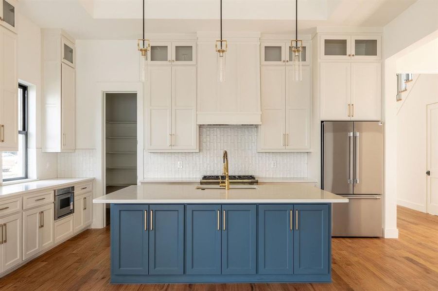 Kitchen with blue cabinets, appliances with stainless steel finishes, glass insert cabinets, and pendant lighting