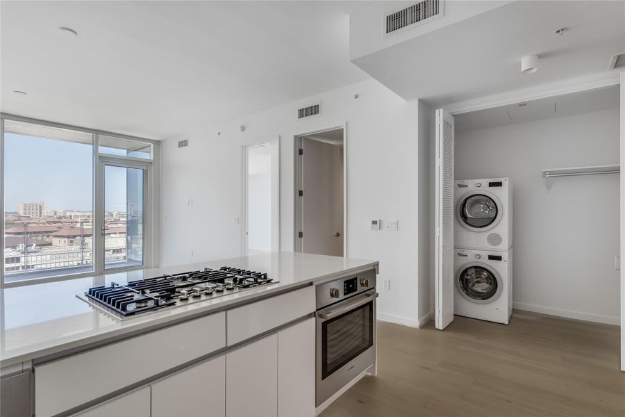 A sleek, contemporary kitchen island with a gas range complements the airy living space and city views. A sleek, contemporary kitchen island with a gas range complements the airy living space and city views.