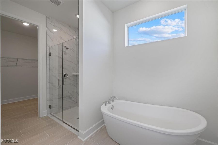 Full bath featuring a walk in closet, a freestanding tub, a marble finish shower, recessed lighting, and wood tiled floors Full bath featuring a walk in closet, a freestanding tub, a marble finish shower, recessed lighting, and wood tiled floors