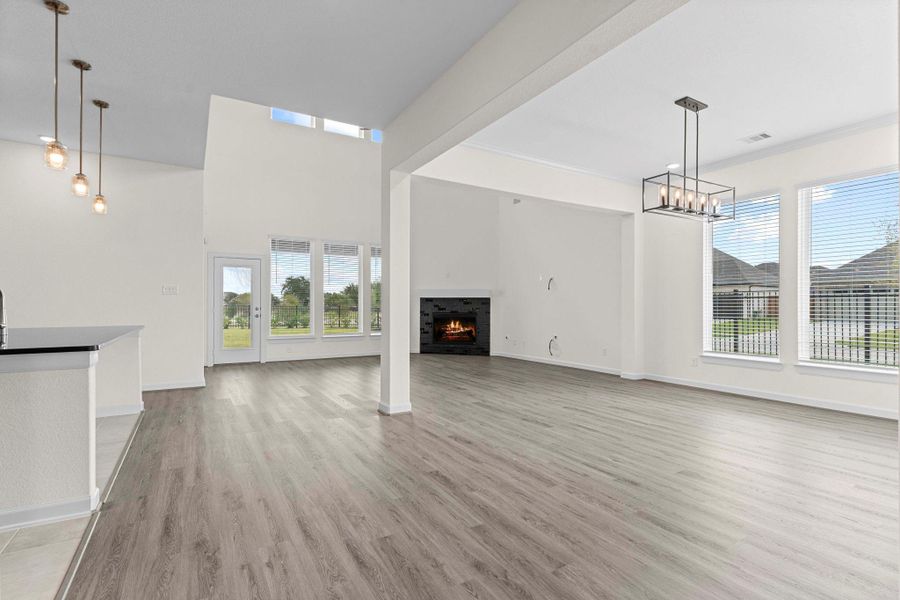 Spacious open-concept family area with dramatic high ceilings, tall windows that invite natural light, and a cozy fireplace centerpiece. Spacious open-concept family area with dramatic high ceilings, tall windows that invite natural light, and a cozy fireplace centerpiece.