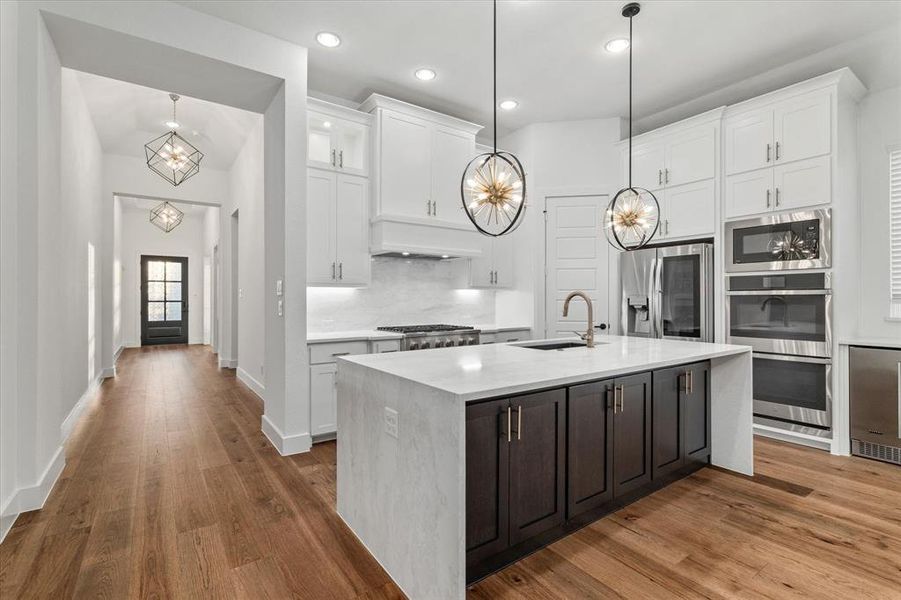 Kitchen featuring a chandelier, light stone countertops, white cabinets, dark wood finished floors, and recessed lighting Kitchen featuring a chandelier, light stone countertops, white cabinets, dark wood finished floors, and recessed lighting