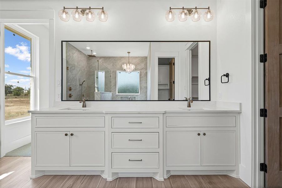 Full bathroom featuring a marble finish shower, double vanity, a chandelier, and light wood-style flooring Full bathroom featuring a marble finish shower, double vanity, a chandelier, and light wood-style flooring