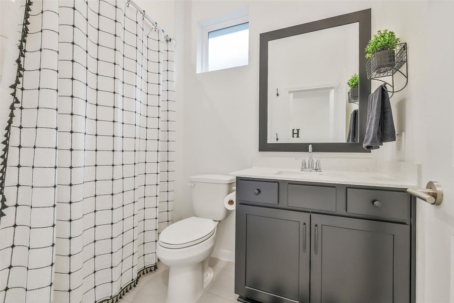 The hall bath features a framed mirror and tub/shower combo. A small, high window maintains privacy while providing natural light.