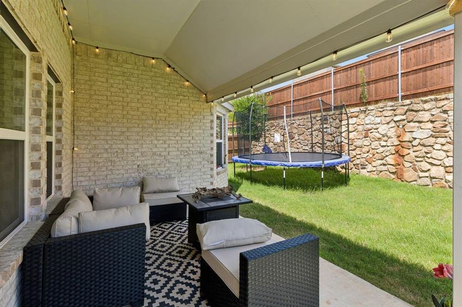 Covered patio with string lighting, brick exterior wall, and concrete flooring