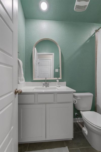 Bathroom featuring a white vanity with an integrated sink, polished chrome faucet, and an arched mirror Bathroom featuring a white vanity with an integrated sink, polished chrome faucet, and an arched mirror